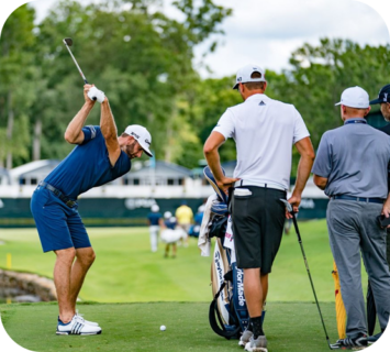Golfer preparing to swing on a lush green course with caddies nearby.