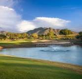 Scenic golf course with a water hazard and mountain backdrop.